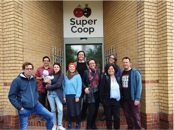 Eine Gruppe Menschen steht vor dem Eingang zum SuperCoop